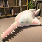 Peluche Requin-Scie rose sur un lit