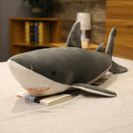 Peluche Requin Cartoon gris sur un lit